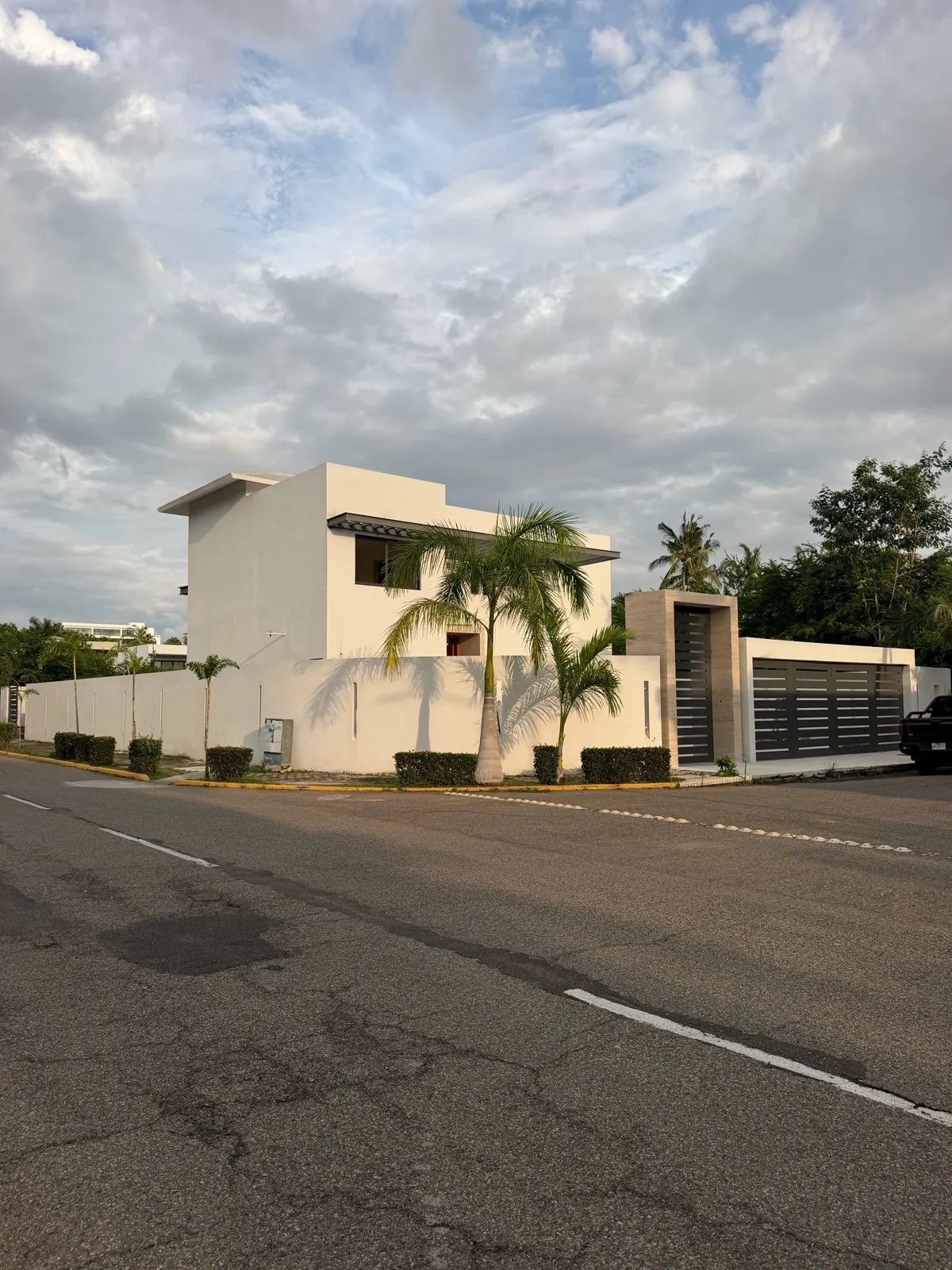 Real photo, Oct 2026. Vehicle entrance, open carport and the pool under construction beside the terrace.